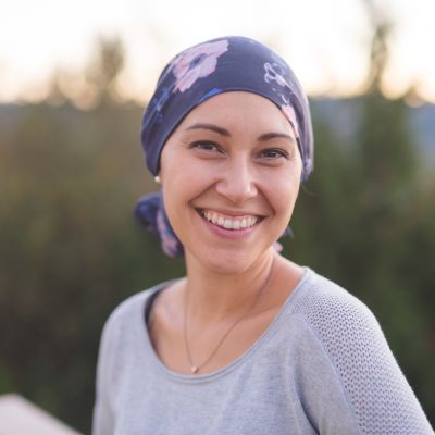 woman with headscarf due to cancer treatment standing outside smiling