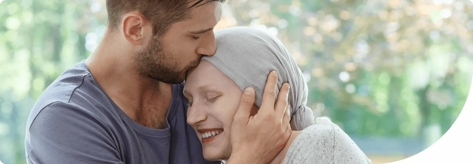man holding woman wearing a scarf over her head due to cancer treatment