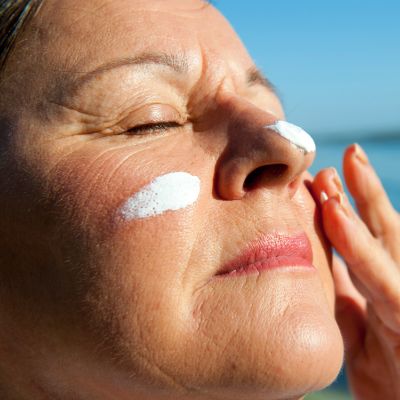 Woman applying sunscreen on her face.