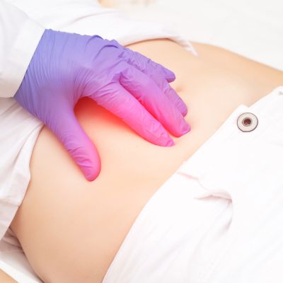 Close-up of a doctor's gloved hand checking a patient's abdomen