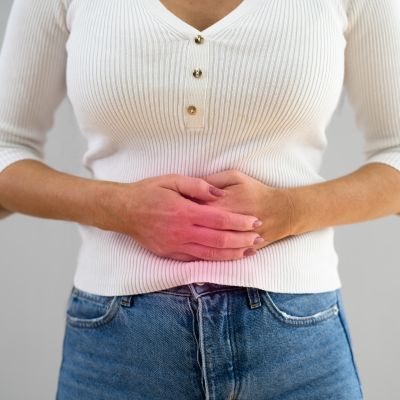 woman holding stomach due to abdominal pain from colon cancer